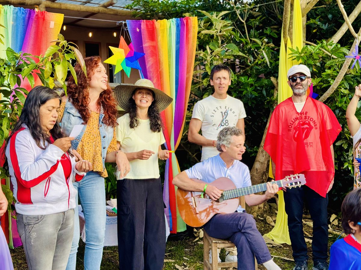 Families singing with a guitar in front of rainbow fabric