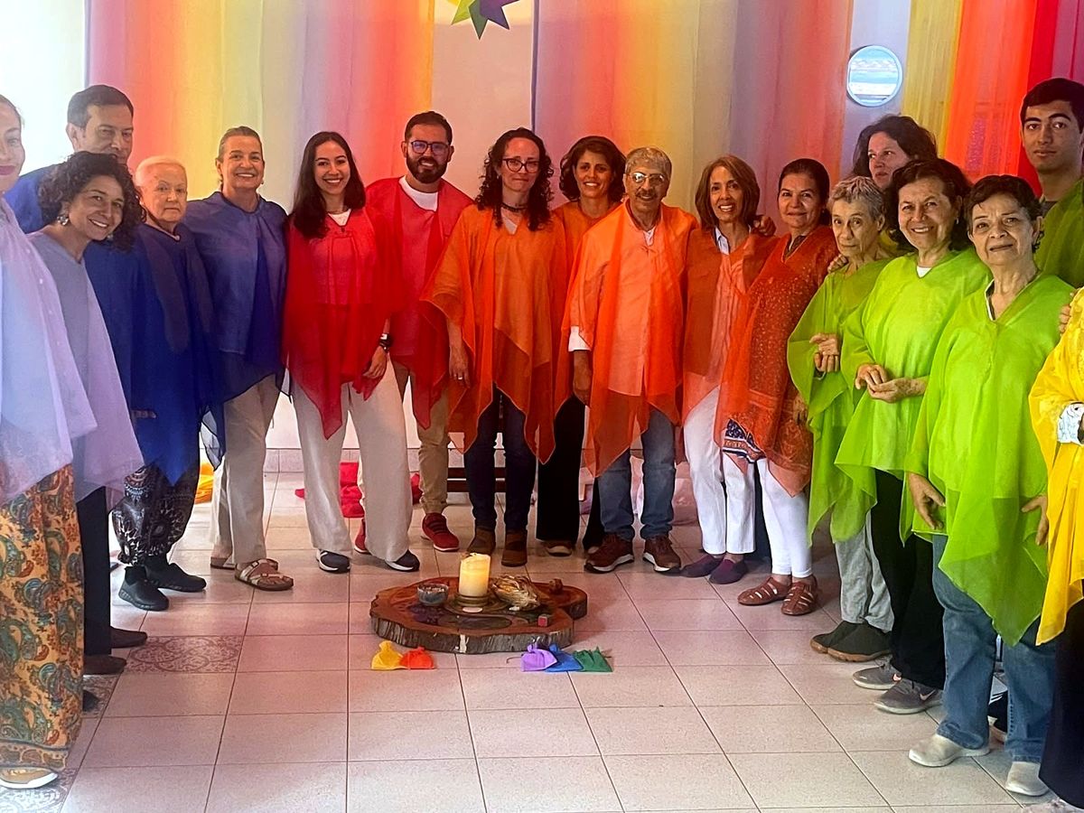 About twenty adults standing in colored veils around a candle at the end of the circle