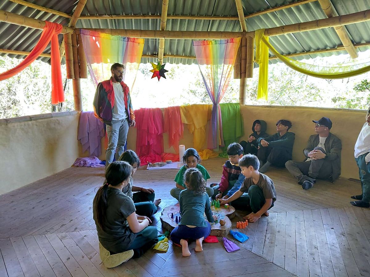 A view of the bamboo gazebo with families playing in a circle around the board