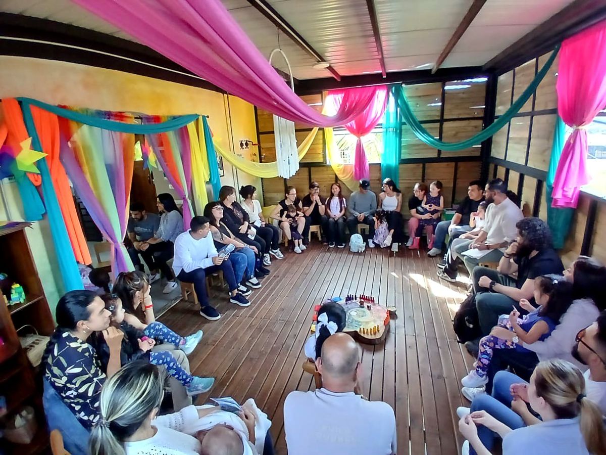 Families sitting in a large circle around the board in a wooden house